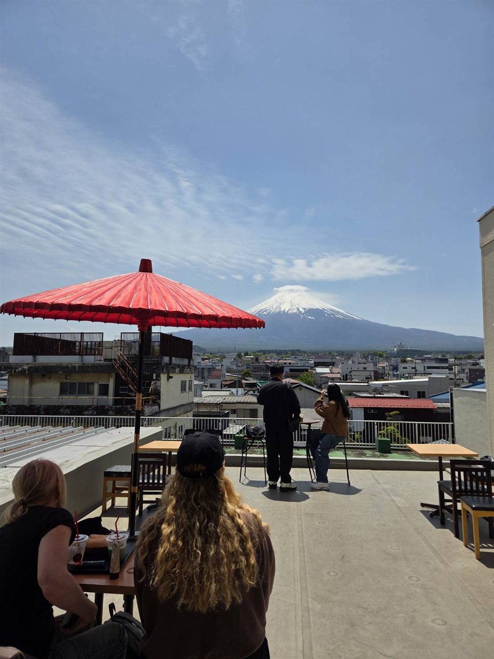 Guests photographing Mt. Fuji from the rooftop under a red parasol